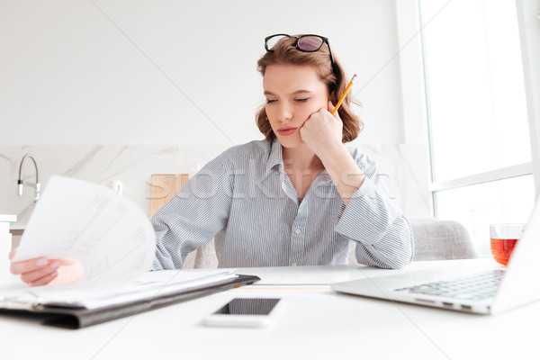 Attractive thinking woman in striped shirt holding her cheek whi Stock photo © deandrobot