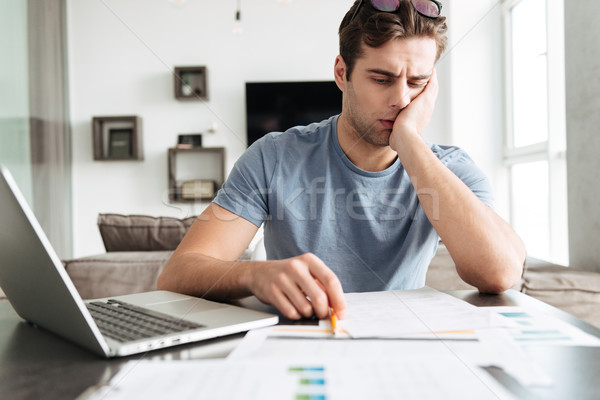 Concentrated tired man working with papers at home Stock photo © deandrobot