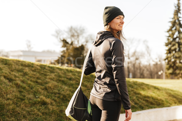 Photo of joyous athletic girl in black sportswear, walking with  Stock photo © deandrobot