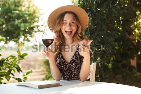 Young woman sitting in cafe drinking wine waving to friends. Stock photo © deandrobot