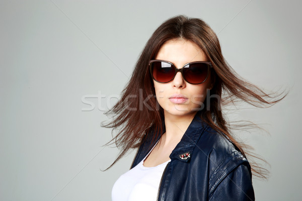 Studio shot of a young model in leather jacket and sunglasses on gray background Stock photo © deandrobot