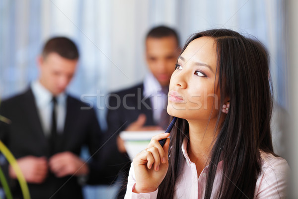 Portrait of young pensive asian woman with her business partners on the background Stock photo © deandrobot