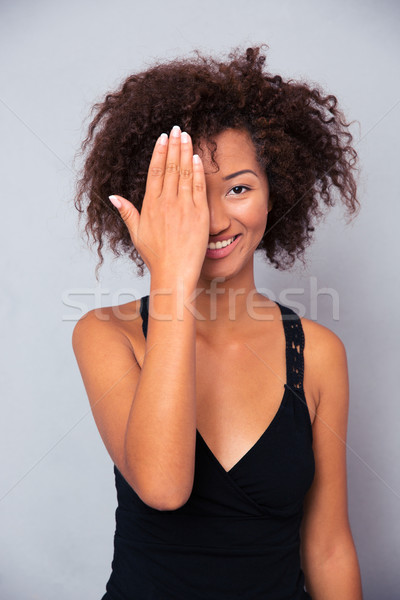 Smiling afro american woman covering her eye Stock photo © deandrobot