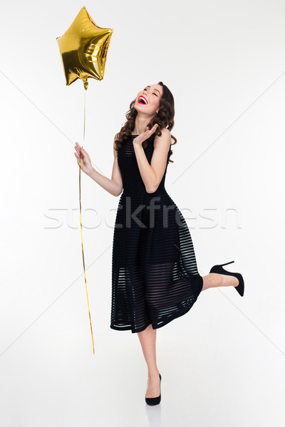 Beautiful happy woman laughing and holding golden star shaped balloon Stock photo © deandrobot