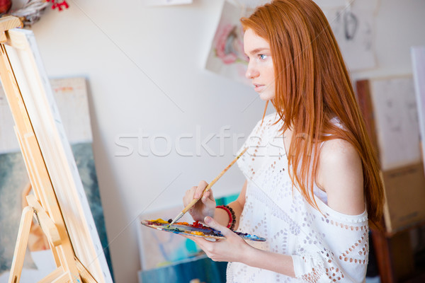 Concentrated pensive woman painter with long hair painting on canvas  Stock photo © deandrobot