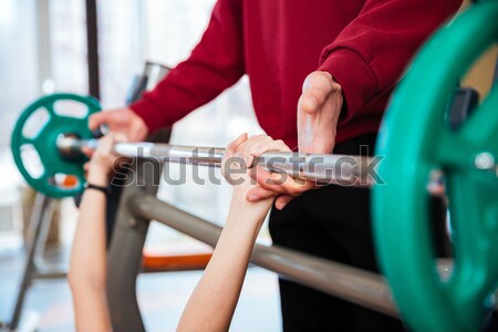 Hands of young sportswoman training with fitness instructor using barbell Stock photo © deandrobot
