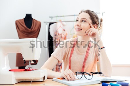 Happy woman seamstress sews on sewing machine in studio Stock photo © deandrobot
