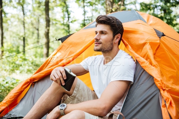 Man tourist with flask sitting at touristic tent in forest Stock photo © deandrobot