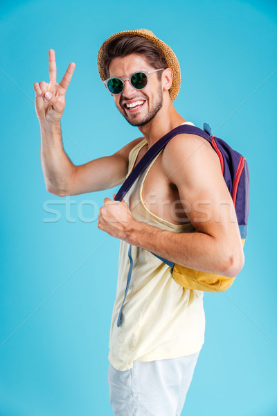Smiling young man with backpack showing peace sign Stock photo © deandrobot