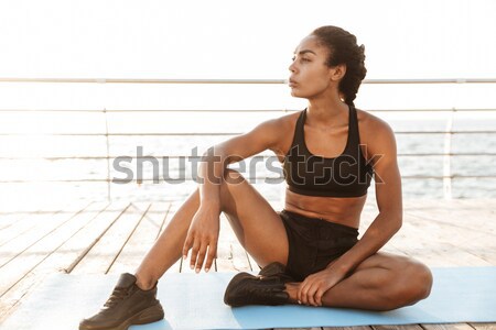 Portrait of a young woman stretching on yoga mat outdoors Stock photo © deandrobot