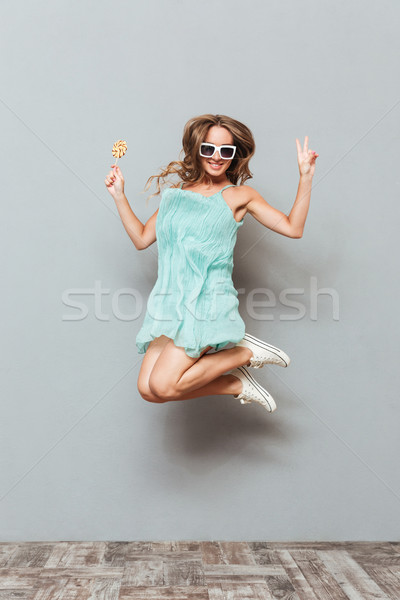 Boldog bájos fiatal nő napszemüveg ugrik levegő Stock fotó © deandrobot