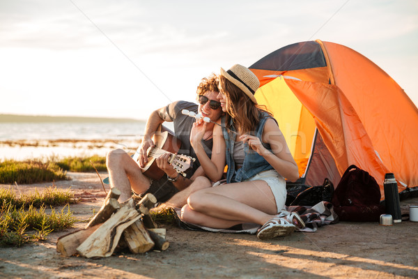 Couple playing guitar and eating fryed marshmallows near touristic tent Stock photo © deandrobot