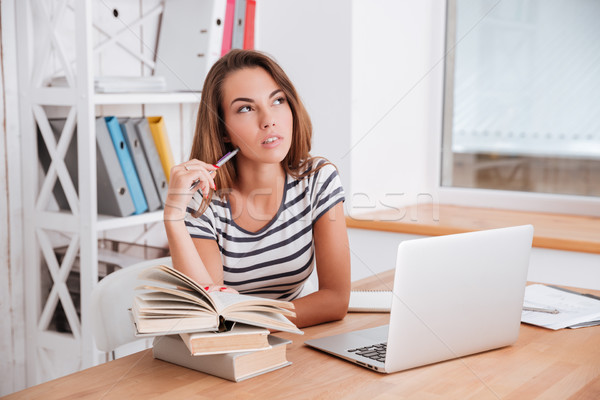 Beautiful student prepares for exams while touching face with pen Stock photo © deandrobot