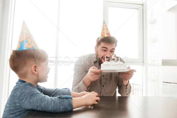 Bearded young father try to eating birtday cake of son. Stock photo © deandrobot
