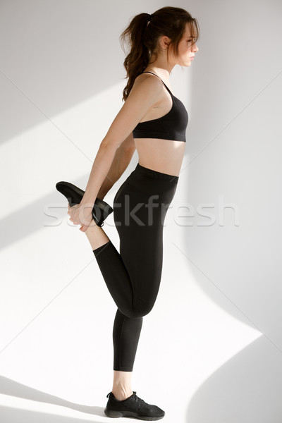 Side view portrait of a young sports woman stretching leg Stock photo © deandrobot