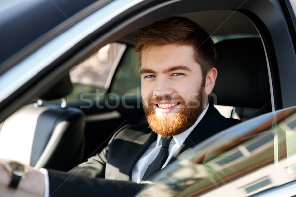 Close up portrait of a smiling bearded man in suit driving car Stock photo © deandrobot