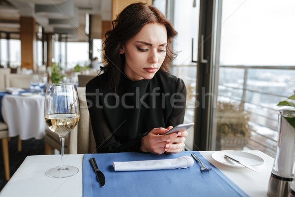 Woman in restaurant writing message on phone Stock photo © deandrobot