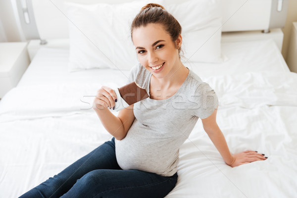 Boldog terhes nő ül ágy eszik csokoládé szelet Stock fotó © deandrobot