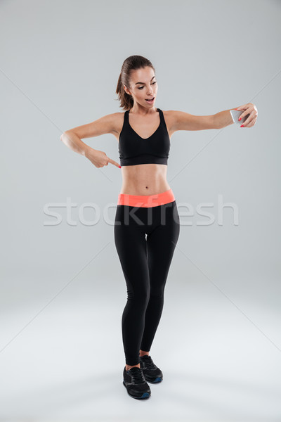 Full length picture of happy fitness woman pointing at abdominals Stock photo © deandrobot