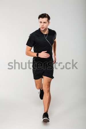 Full length portrait of a fit man athlete in earphones Stock photo © deandrobot