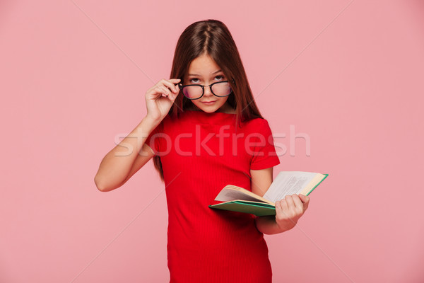 Stock photo: Serious girl nerd in dress looking through glasses while reading