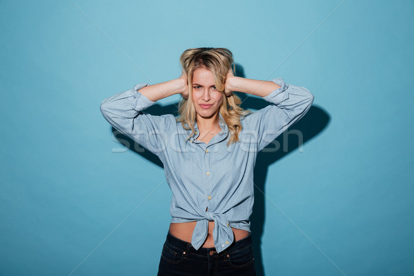 Displeased blonde woman in shirt covering her ears Stock photo © deandrobot