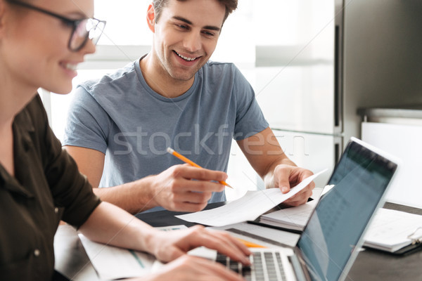 Smiling lovers work with her man at home with laptop Stock photo © deandrobot