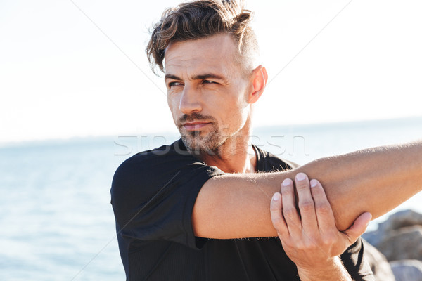 Attractive sportsman doing stretching exercises Stock photo © deandrobot