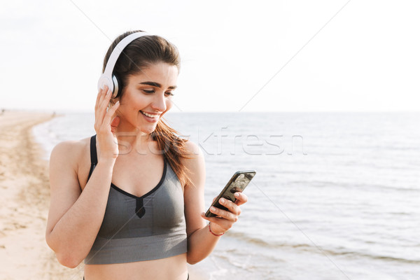 Szczęśliwy młodych sportsmenka stałego plaży słuchanie muzyki Zdjęcia stock © deandrobot