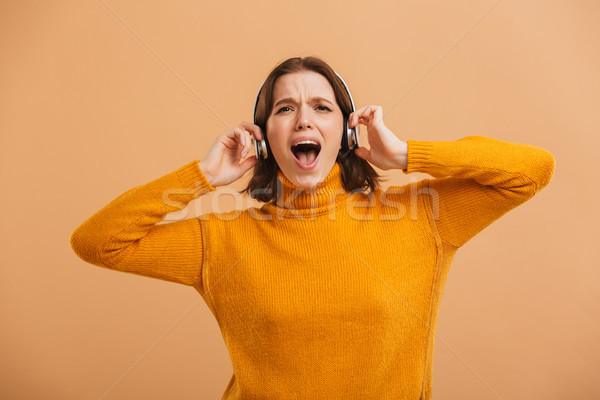 Emotional beautiful young woman listening music with headphones singing. Stock photo © deandrobot