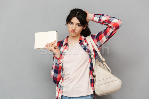 Sad displeased young lady holding book. Stock photo © deandrobot