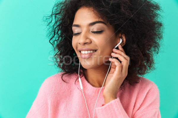 Portrait of beautiful woman with curly dark hair listening to mu Stock photo © deandrobot
