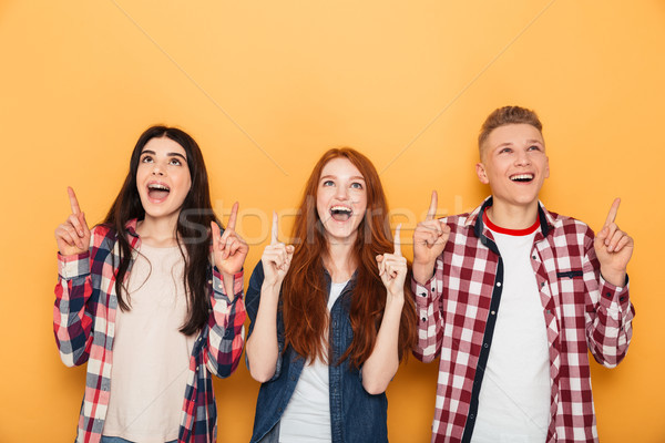 Group of happy school friends pointing fingers up Stock photo © deandrobot