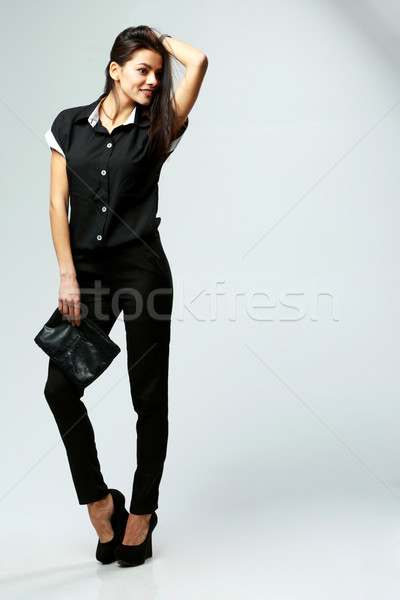 Young happy woman in black formal clothes standing on gray background Stock photo © deandrobot