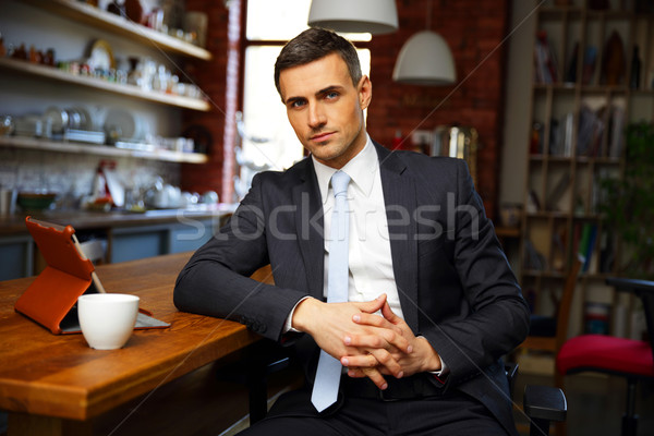 Confident businessman in formal cloths drinking coffee and reading news in the kitchen Stock photo © deandrobot