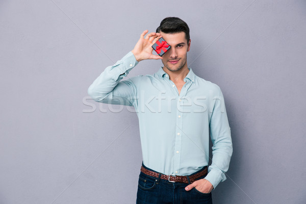 Handsome man covering his eye with gift box Stock photo © deandrobot