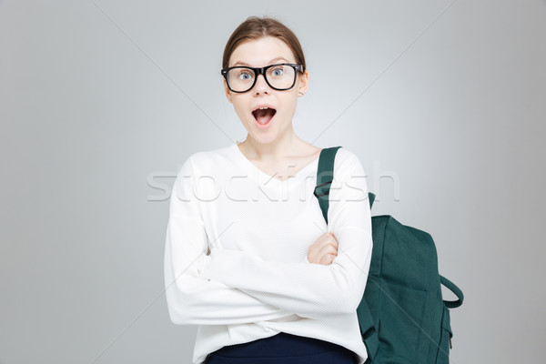 Amazed charming teenage girl in glasses standing with opened mouth  Stock photo © deandrobot