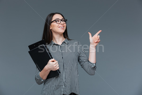 Businesswoman holding folders and pointing finger Stock photo © deandrobot