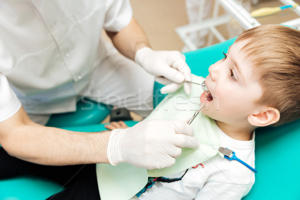 Dentist examining little boy teeth with mirror and hook Stock photo © deandrobot