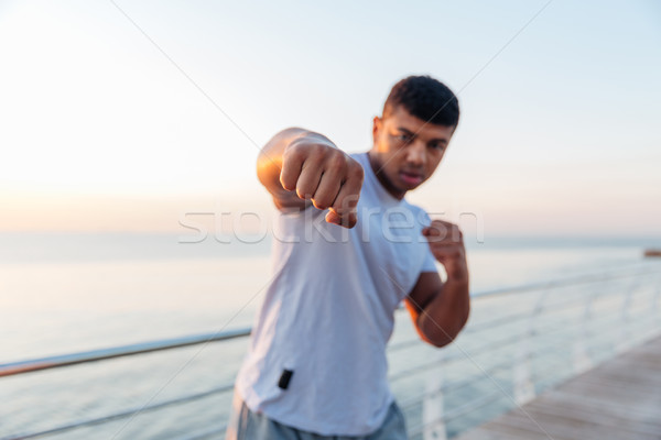 Athletic african man boxer doing boxing training on pier Stock photo © deandrobot