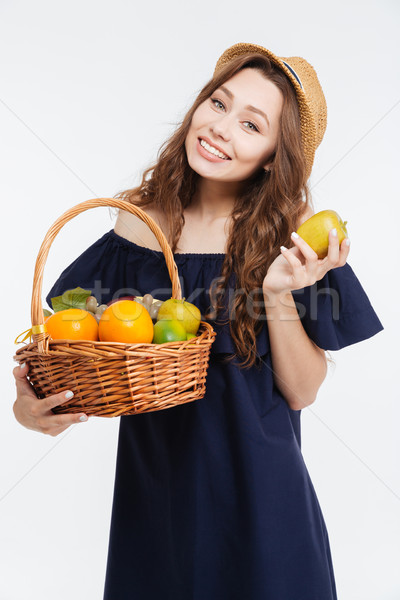 Cheerful cute young woman in hat holding basket with fruits Stock photo © deandrobot