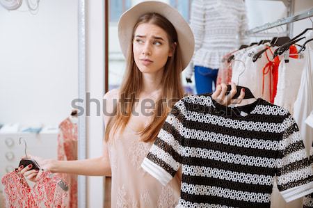 Attractive young woman trying on dress in front of mirror Stock photo © deandrobot