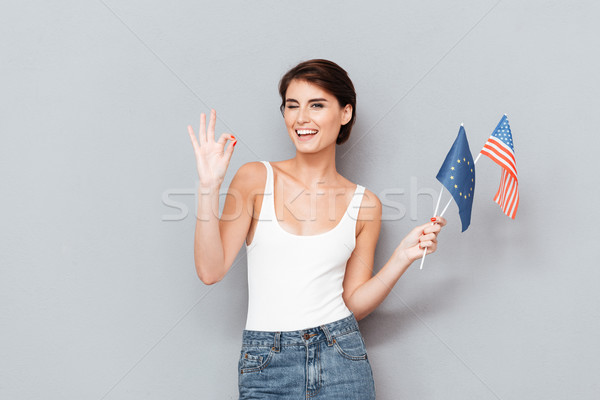 Young woman winking and holding flags Stock photo © deandrobot