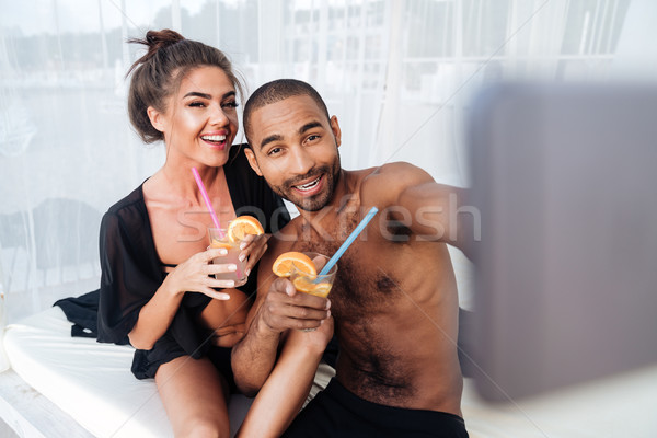 Multiracial couple making selfie and holding cocktails at the beach Stock photo © deandrobot