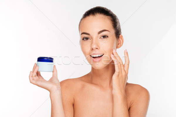Young woman putting cream on her face Stock photo © deandrobot