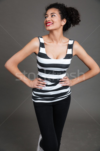 Cheerful pretty african young woman standing with hands on waist Stock photo © deandrobot