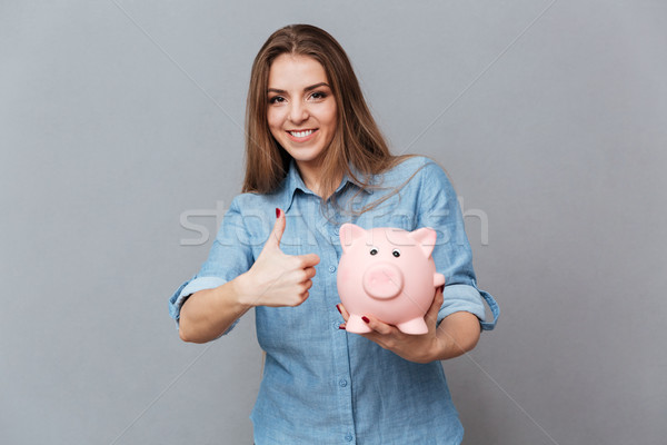 Smiling Woman in shirt holding moneybox in hand Stock photo © deandrobot
