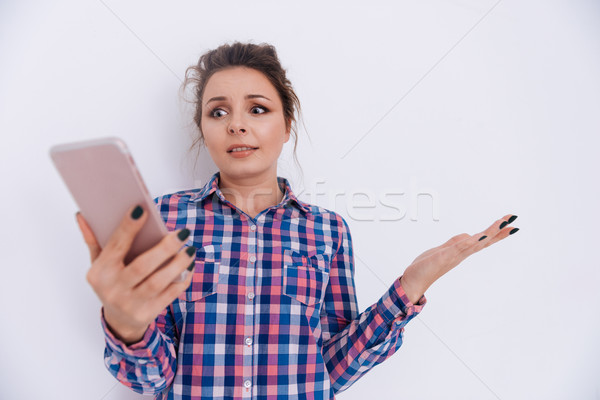 Meglepődött nő kockás póló telefon tart Stock fotó © deandrobot