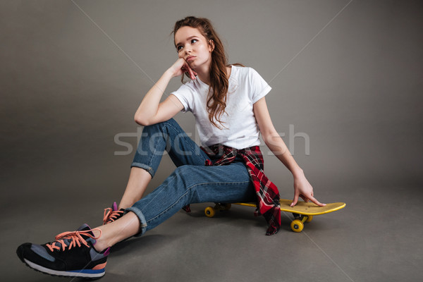 Portret jonge tienermeisje vergadering skateboard grijs Stockfoto © deandrobot