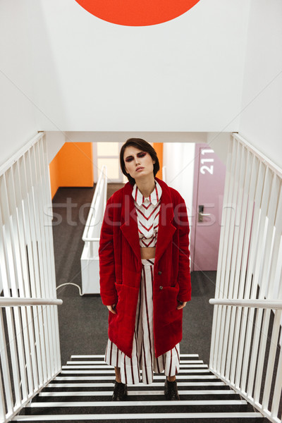 Woman in red coat standing on stairs Stock photo © deandrobot